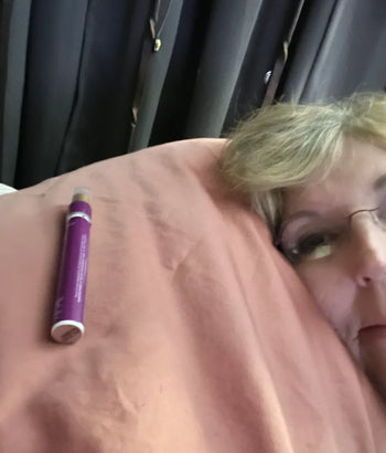 Person lying down with a purple sleep spray on their chest