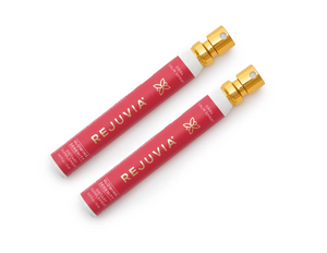 Two red REUVIVIA products with gold caps on a white background