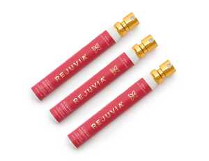 Three red REJUVIA products with gold caps on a white background