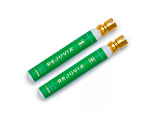 Two green REJUVIA products with gold caps on a white background