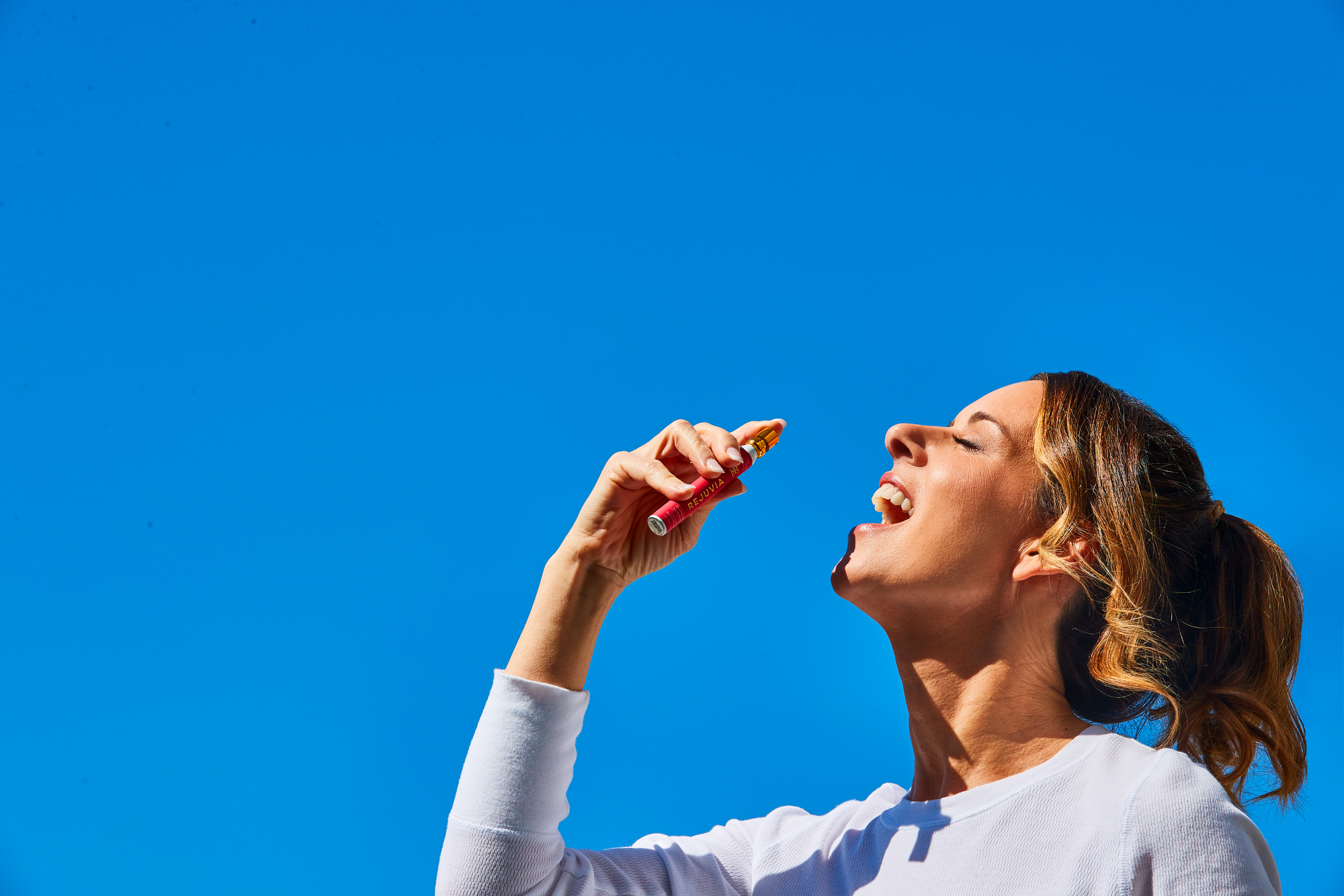 Woman using rejuvia stress spray in sky